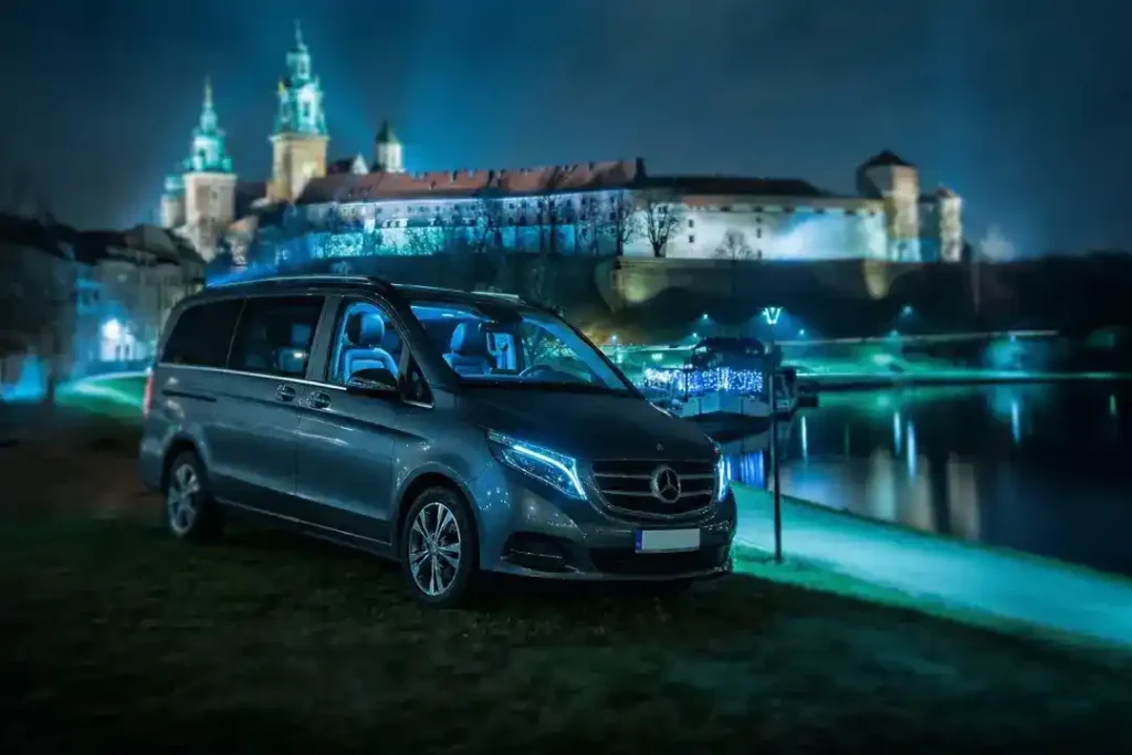 Mercedes minivan for private tours from Kraków parked beside Wawel Castle at night